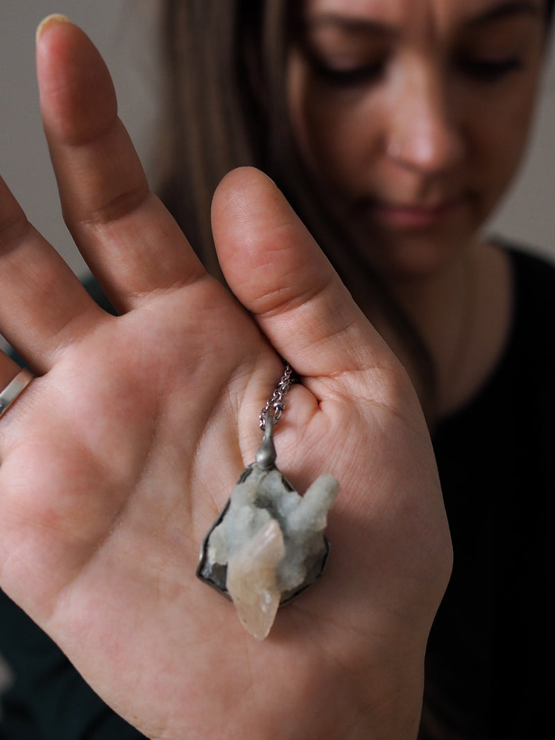 palm of hand with pale blue raw healing crystal talisman necklace