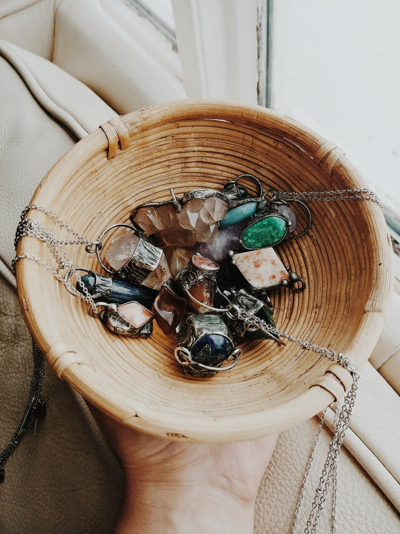 crystal talisman necklaces in small wicker bowl