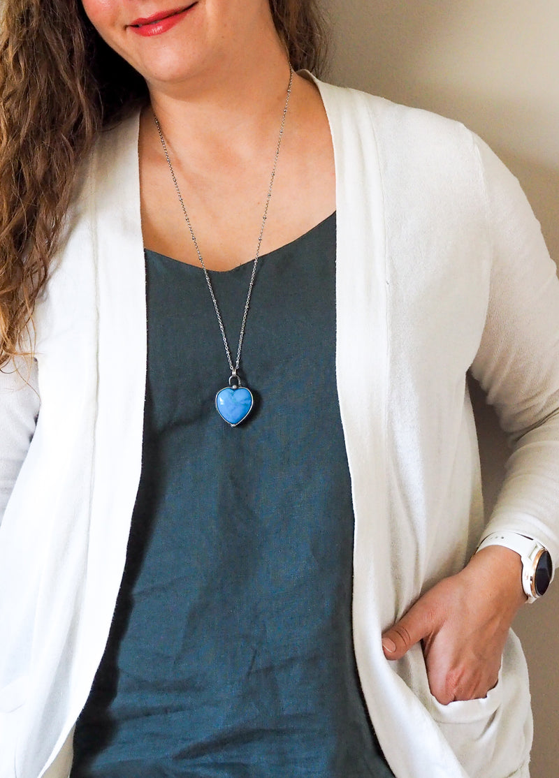 blue gemstone heart crystal necklace talisman on woman in blue top with white cadigan