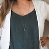 small blue turquoise healing crystal talisman necklace on woman wearing blue top