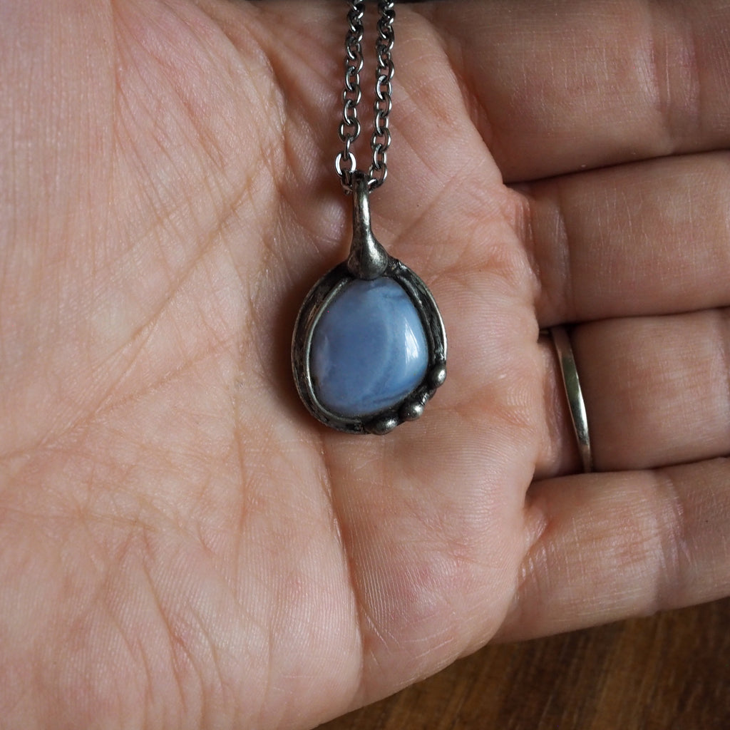 pale blue healing crystal talisman necklace in palm of hand