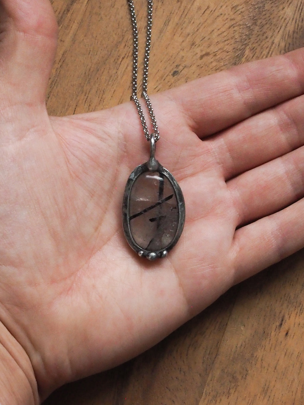 clear and black healing crystal talisman statement necklace in palm of hand