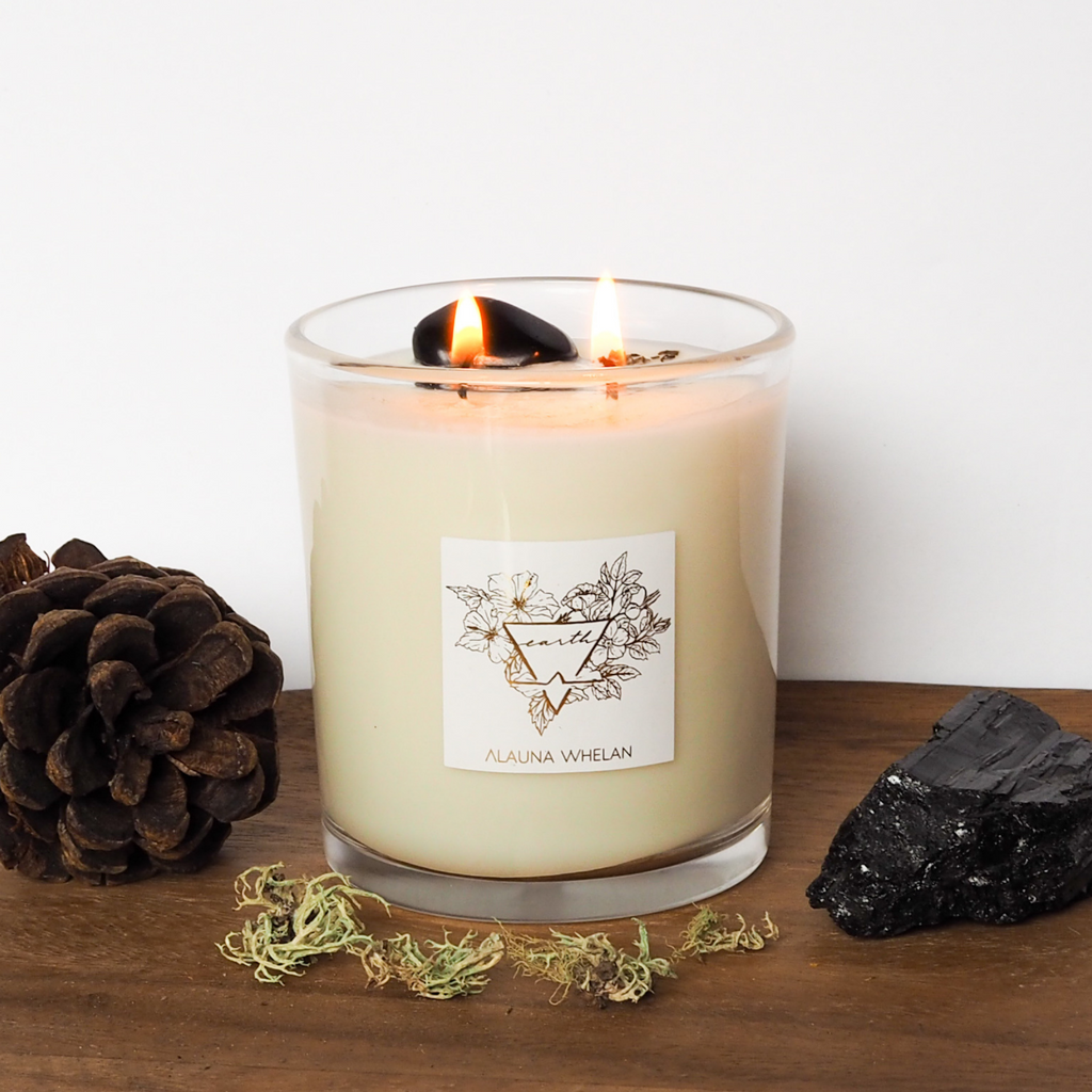 lit soy candle with black gemstone on wooden tray