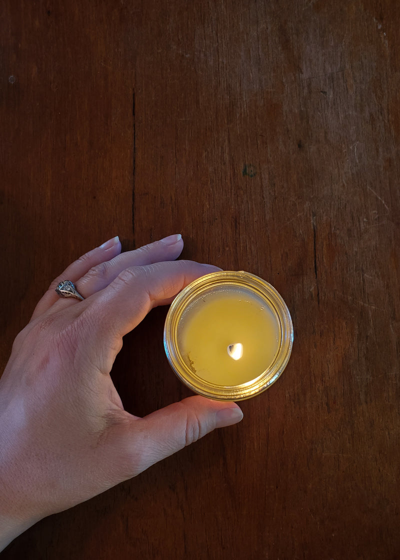 Hand holding jar candle on wooden table