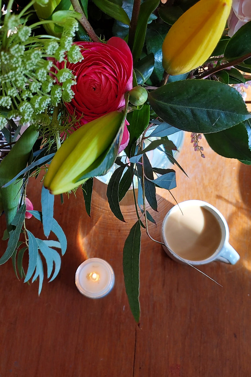 Spring bouquet with candle and coffee on wood table