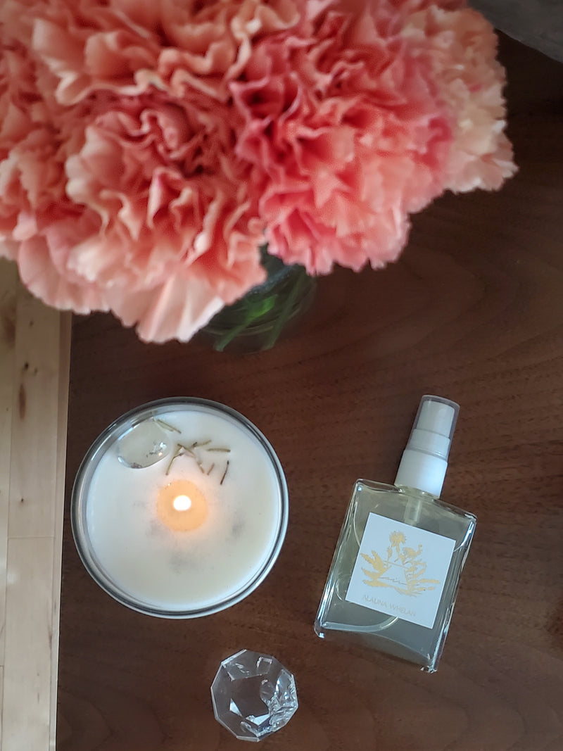 birds eye view of luxury soy candle and ritual mist with pink flowers and crystals