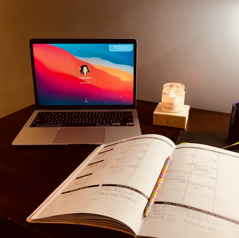 solstice candle with laptop and journal on desk