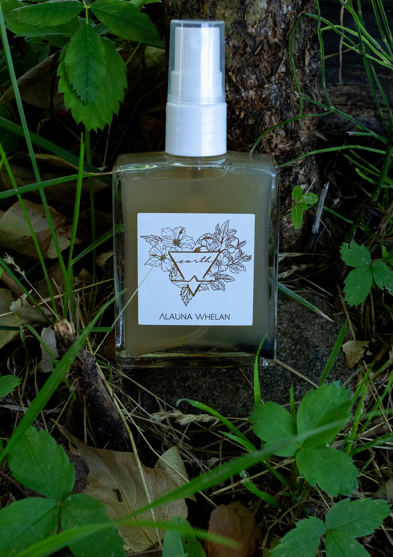 crystal infused ritual mist with white and gold label on forest floor