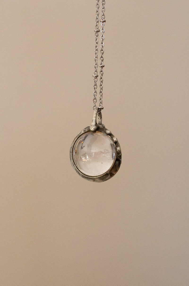 crystal ball necklace with chain on grey background