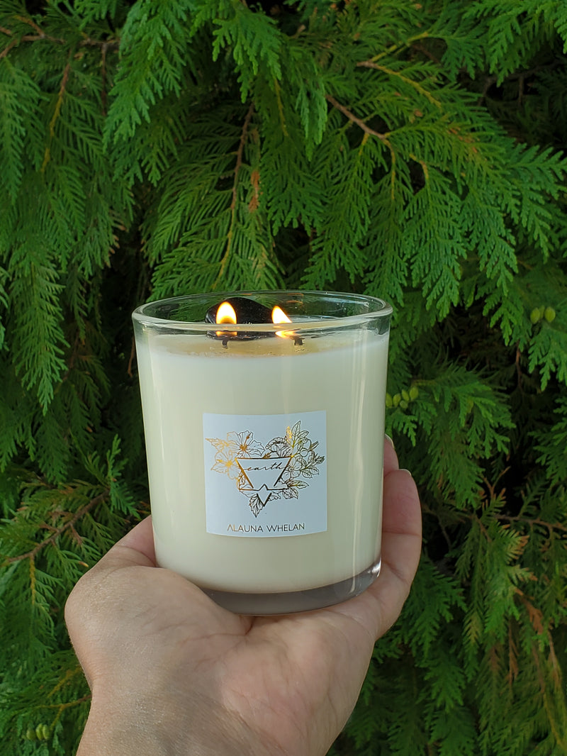 luxury soy earth sign candle in palm of hand with cedar boughs