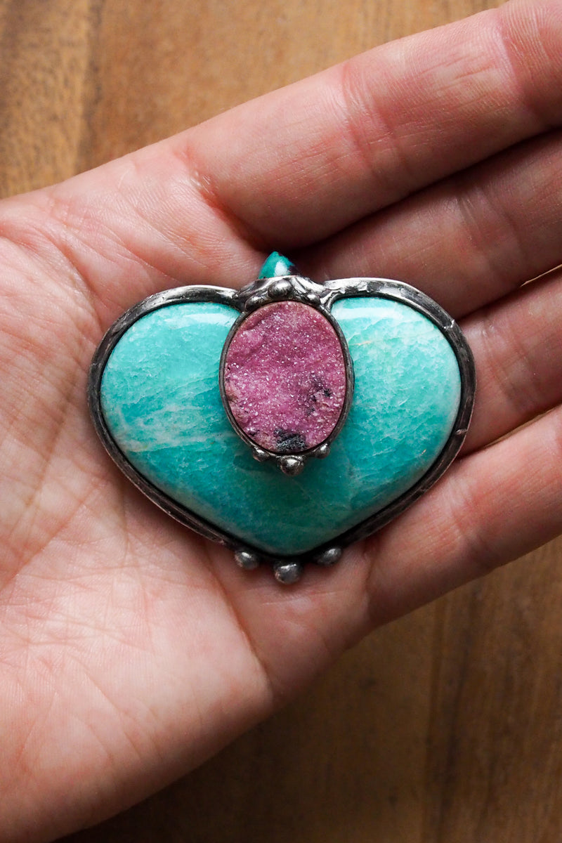 green and pink crystal heart in palm of hand