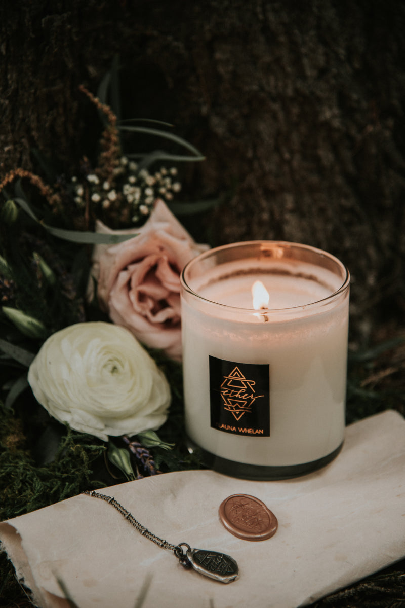 luxury candle with blush toned florals, wax seal and silver medallion necklace