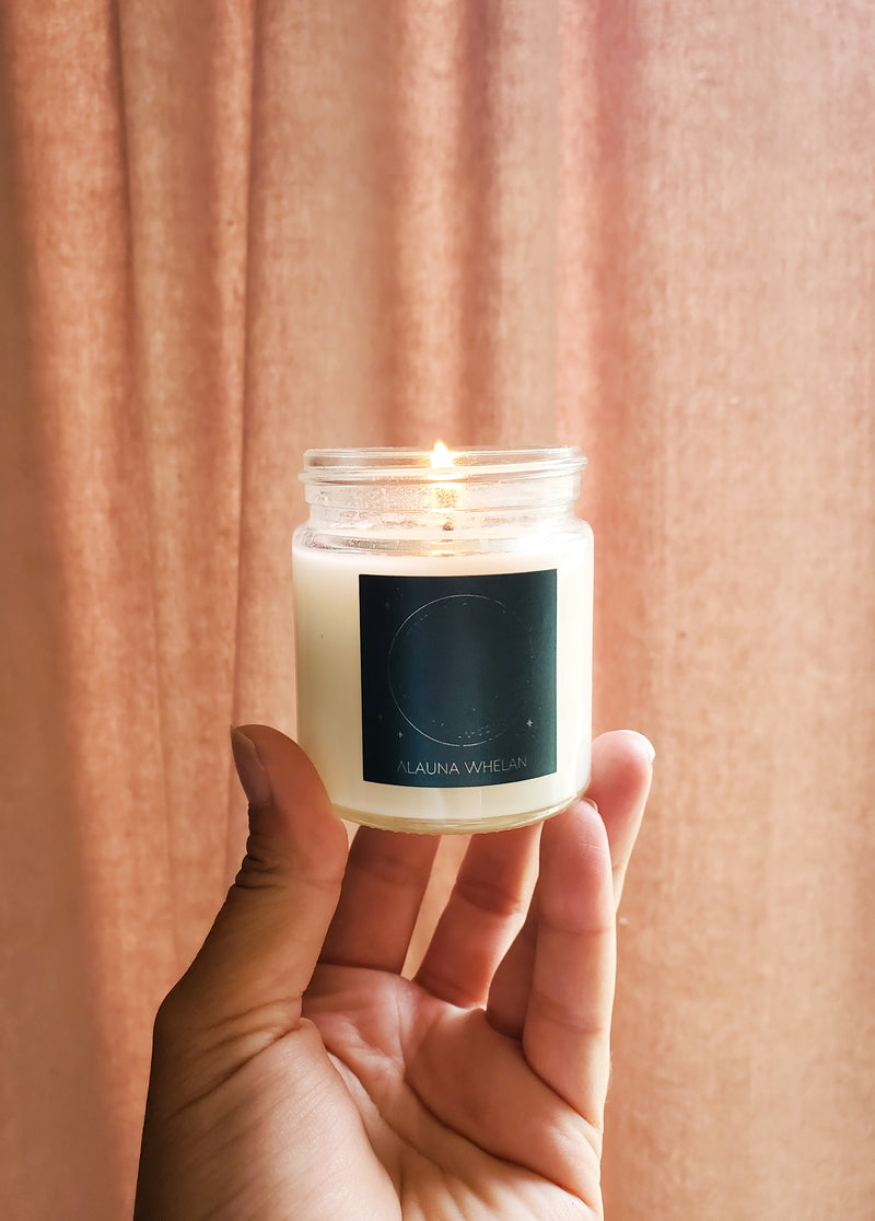 luxury soy candle for new moon in palm of hand with grey velvet backdrop
