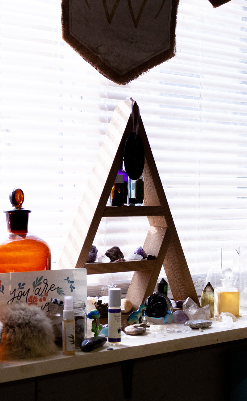 window with apothecary shelf, raw crystals, bottles, perfumes and mists