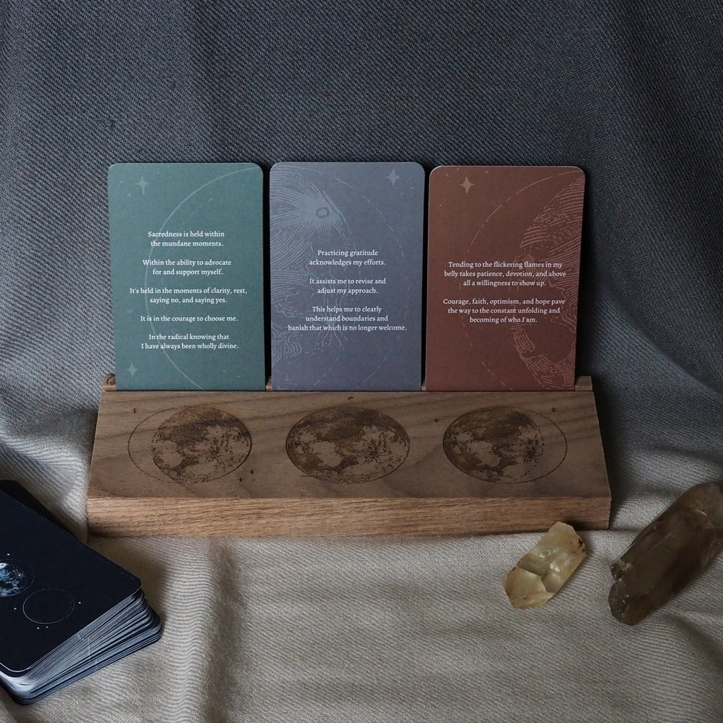 wooden tarot stand with lunar engraving and three tarot cards on soft grey background