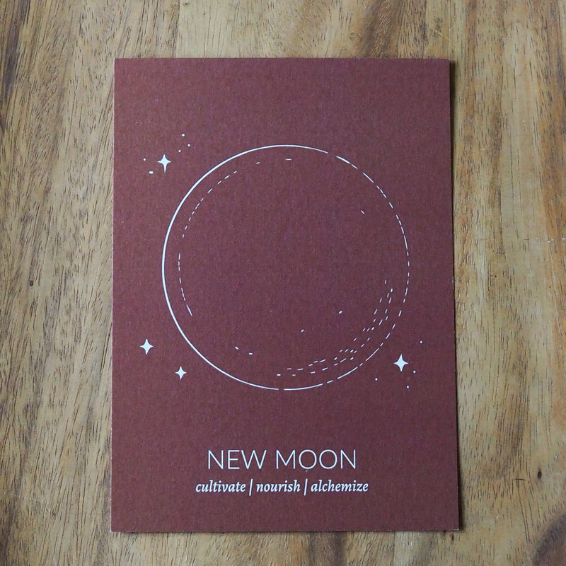 new moon print on rust colored paper on wooden background