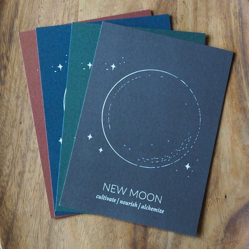 four full moon prints in different colors - rust, blue, green, grey on wooden background