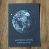 grey waning moon lunar print on wooden background
