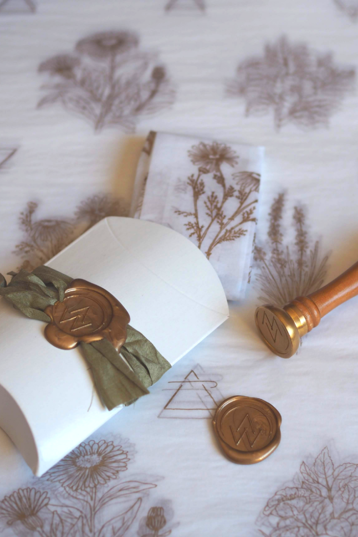luxury packaging featuring wax seal, silk ribbon, and tissue paper with botanical prints