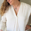 woman in white top wearing a silver full moon lunar talisman layering necklace with rainbow moonstone crystal