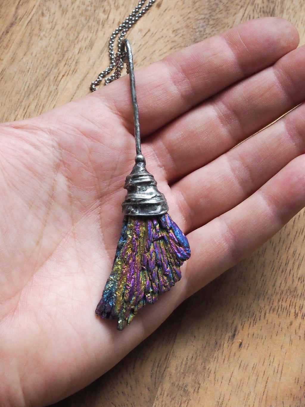 hand holding rainbow besom witches broom healing crystal talisman necklace