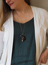 woman in blue top wearing large grey healing talisman crystal statement necklace