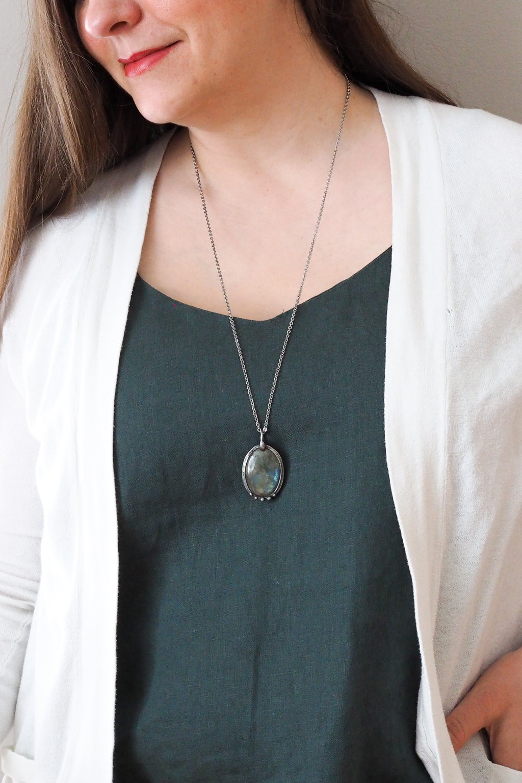 blue and green flashy labradorite gemstone healing crystal talisman statement necklace on woman in blue top with white cardigan
