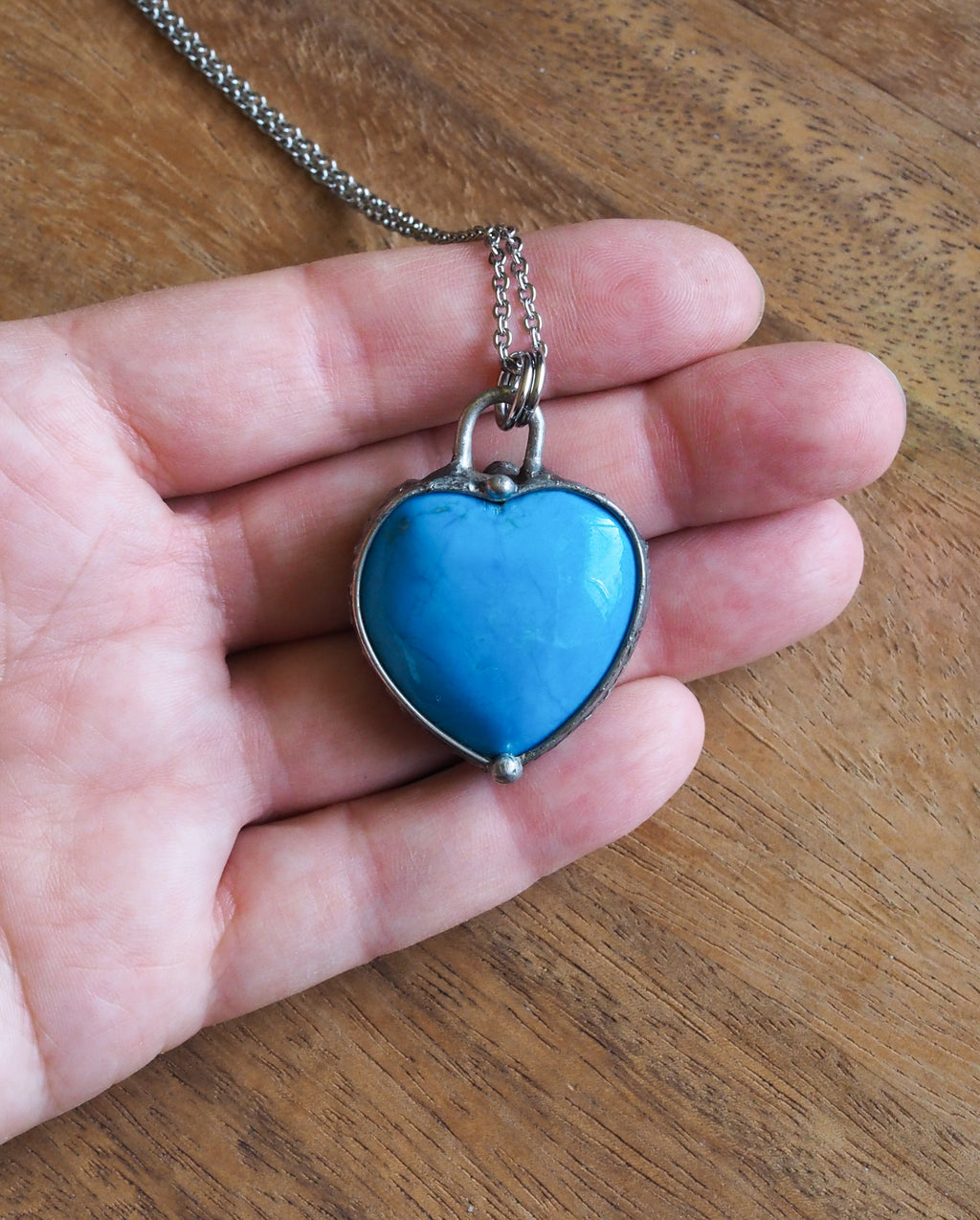 blue gemstone heart crystal necklace talisman in palm of hand