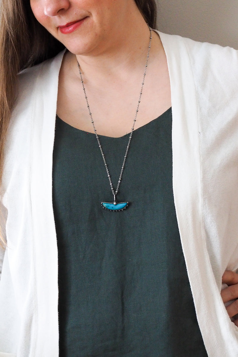 bright blue kingman turquoise gemstone healing crystal talisman statement necklace on woman in blue top with white cardigan