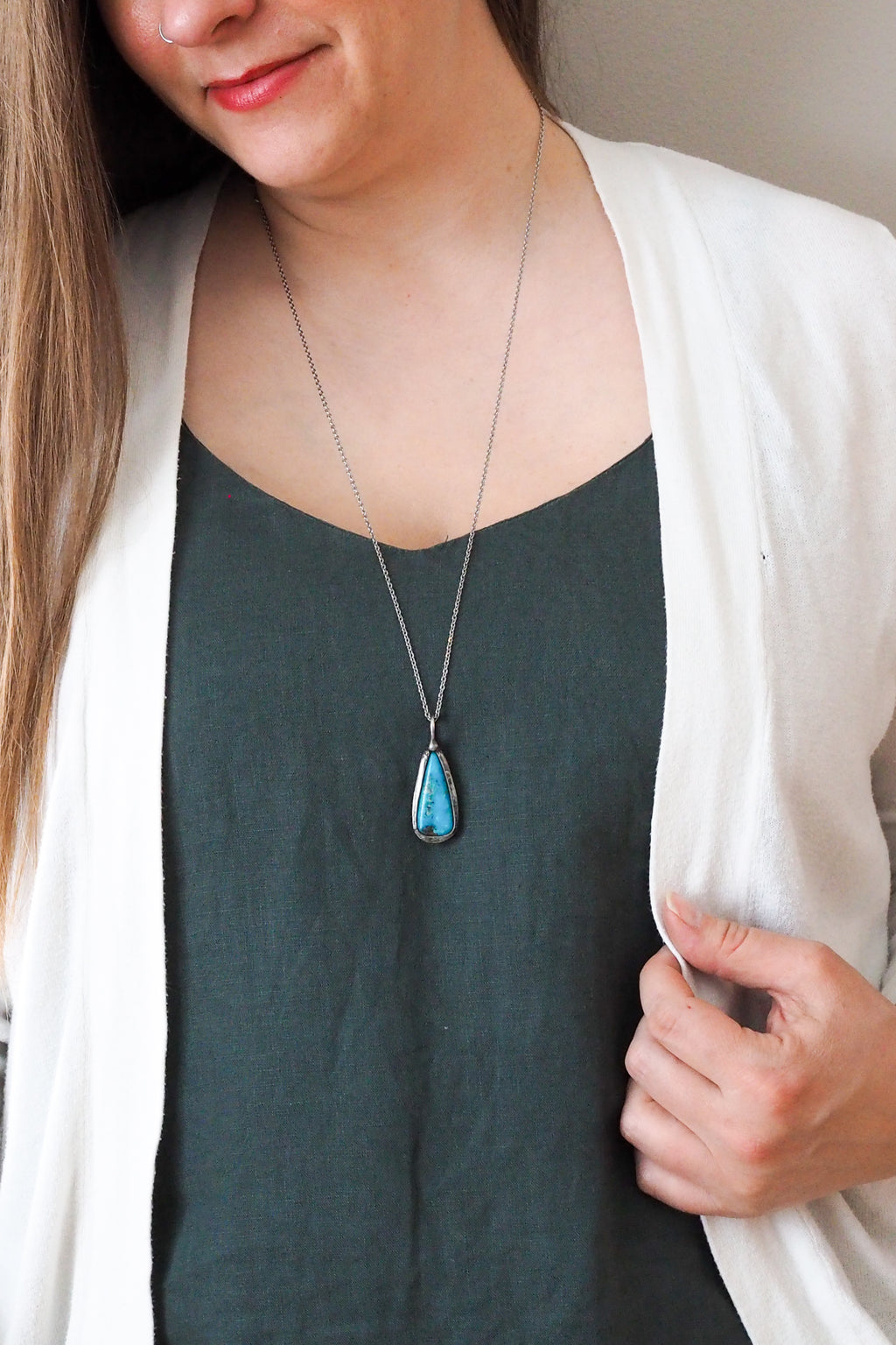 bright blue kingman turquoise gemstone healing crystal talisman statement necklace on woman in blue top with white cardigan