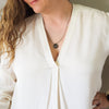 bronze air element layering talisman necklace on woman in white top