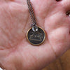 bronze air element layering talisman necklace in palm of hand