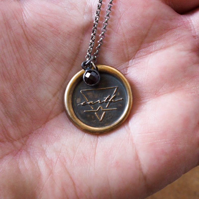 bronze earth sign layering talisman necklace in palm of hand