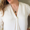 bronze earth sign layering talisman necklace on woman in white silk top