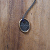 bronze ether element layering talisman necklace on wooden background