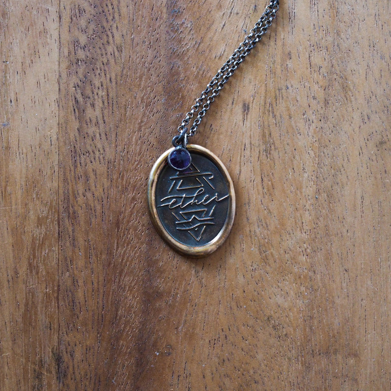bronze ether element layering talisman necklace on wooden background