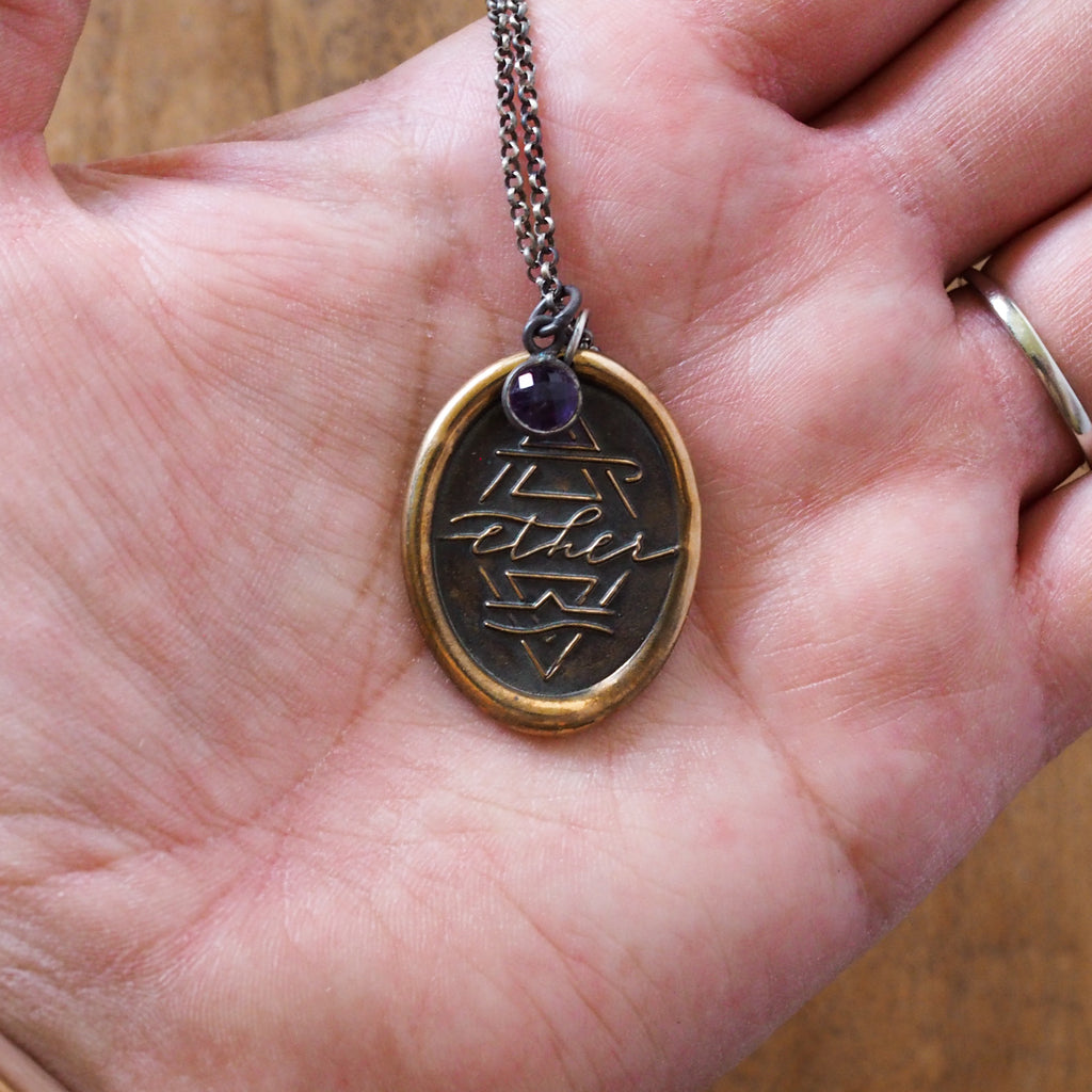 bronze ether element layering talisman necklace in palm of hand