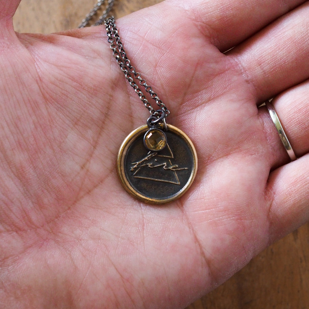 bronze fire element layering talisman necklace in palm of hand