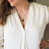 bronze water element layering talisman necklace on woman in white top