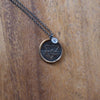 bronze water element layering talisman necklace on wooden background