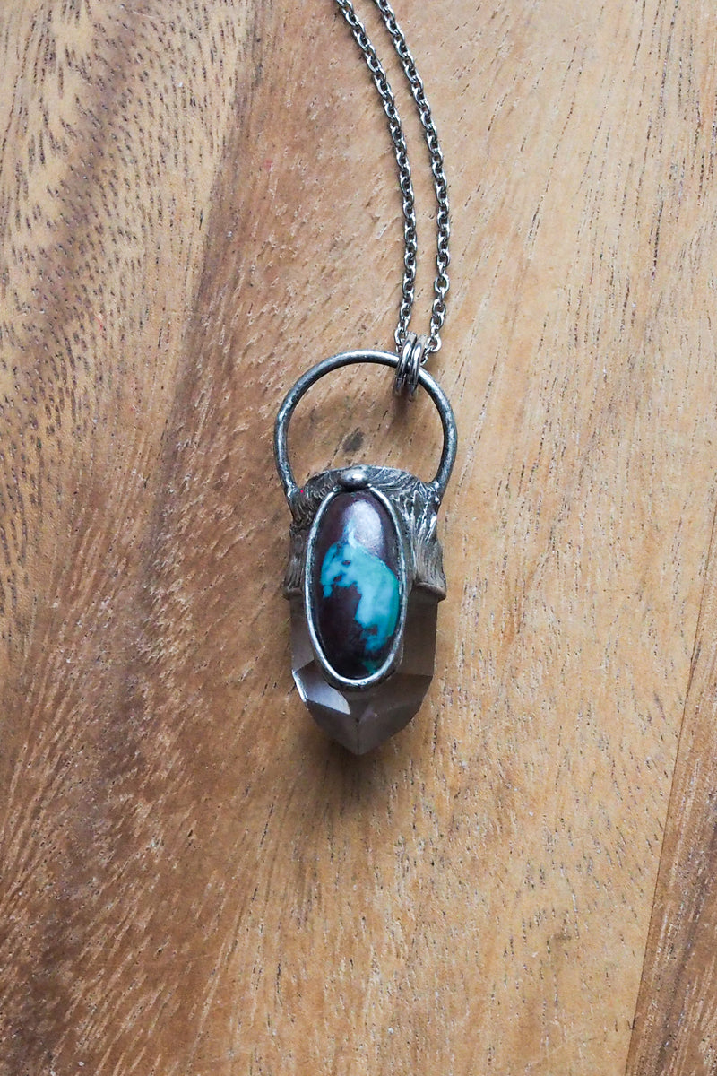 brown, blue, and clear gemstone healing crystal talisman statement necklace on wooden background