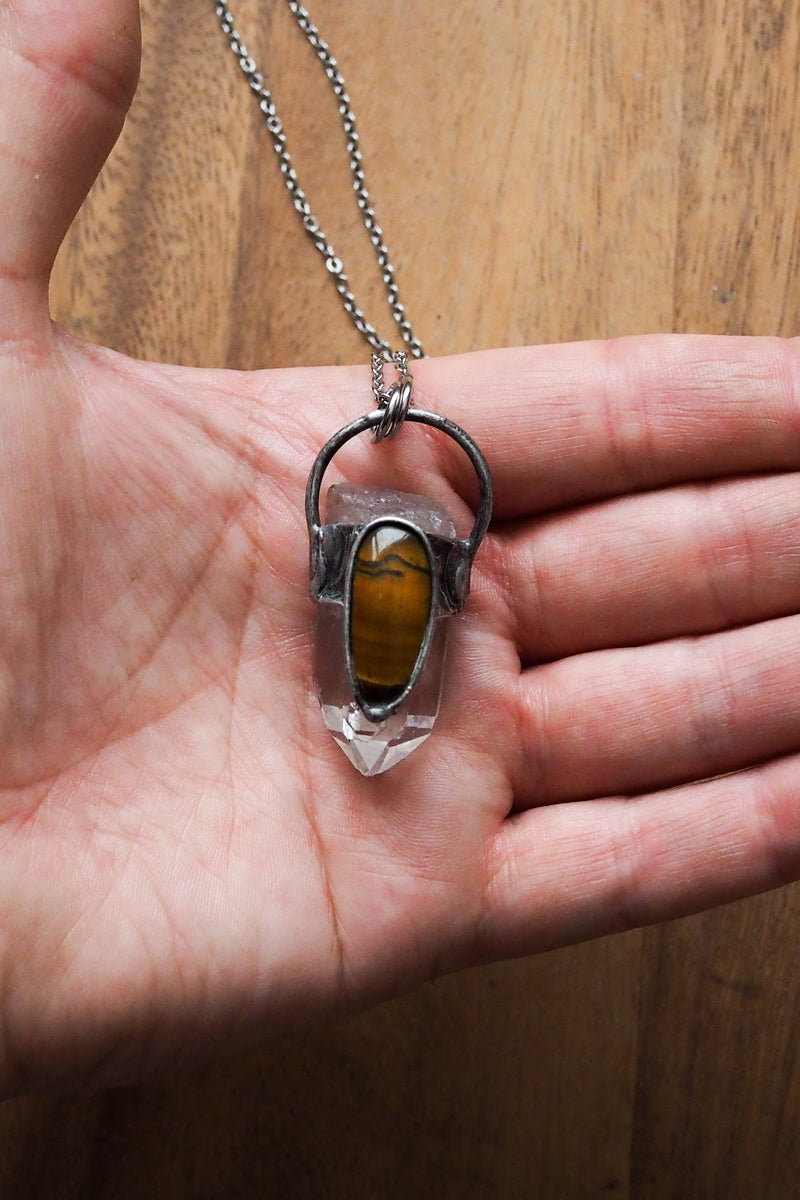 rustic clear and banded yellow healing crystal talisman necklace in palm of hand