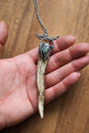hand holding healing crystal talisman necklace made from a deer antler and green gemstone