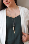 woman in blue top wearing healing crystal talisman necklace made from a deer antler and green gemstone