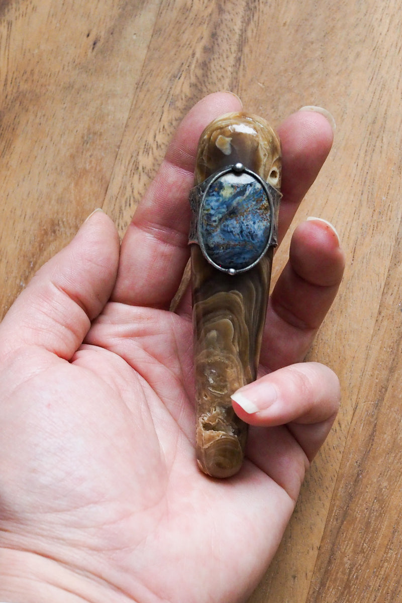 hand holding brown and blue healing crystal talisman wand