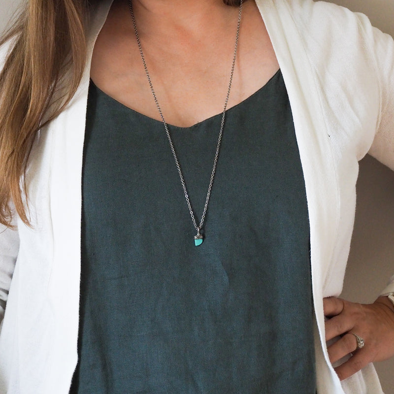 small blue turquoise healing crystal talisman necklace on woman wearing blue top