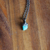 small blue turquoise healing crystal talisman necklace on wooden background