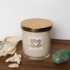 soy candle with green gemstone and seashells on wooden tray