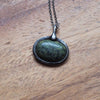 green healing talisman crystal necklace on wooden background