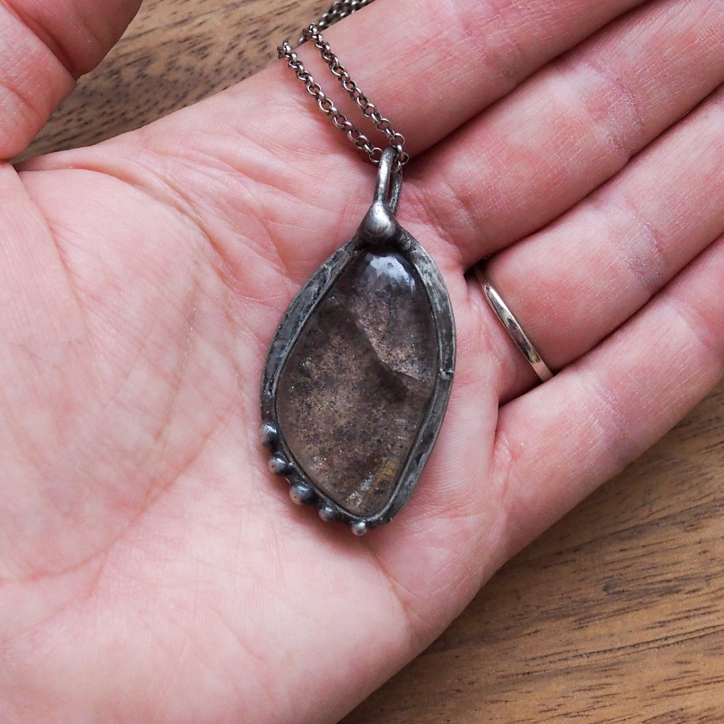 palm of hand holding garden quartz healing crystal talisman necklace